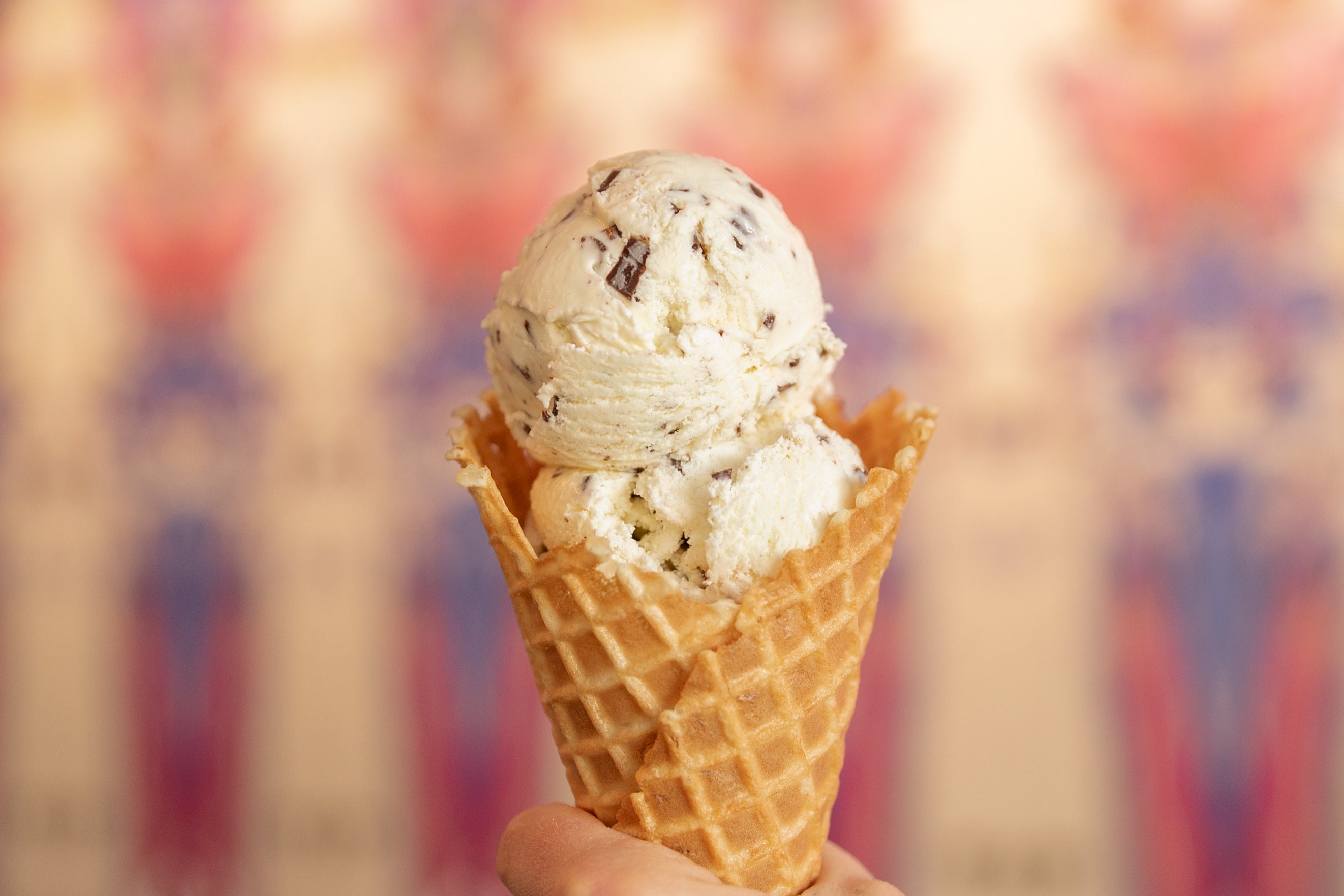 Ice cream cone with two scoops of mint chip ice cream against a colorful blurred background