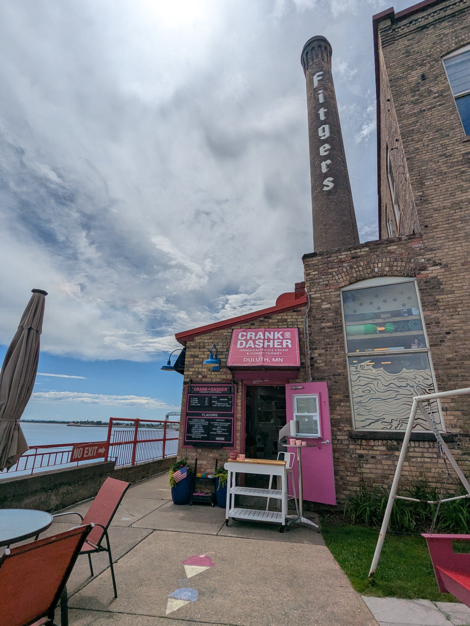 Brick building with outdoor seating area and cloudy sky next to Lake Superior