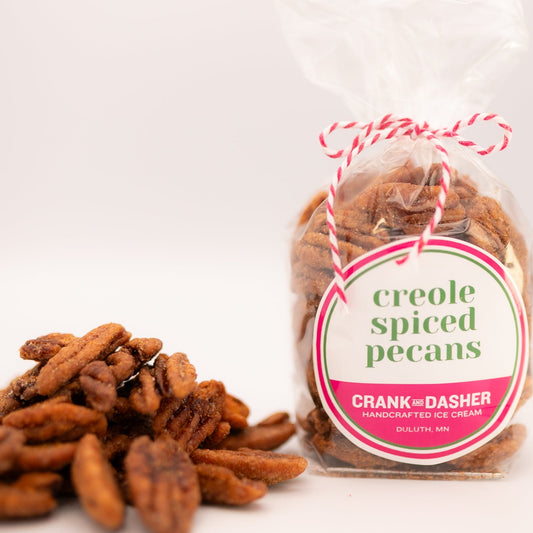 Creole spiced pecans in a clear container with a pink label on a white background