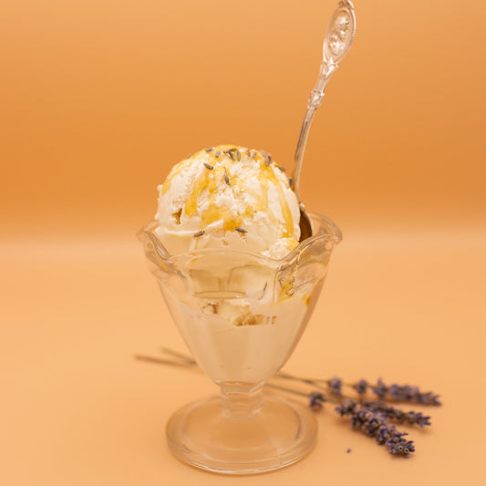 Glass sundae dish with ice cream and lavender flowers on a peach background