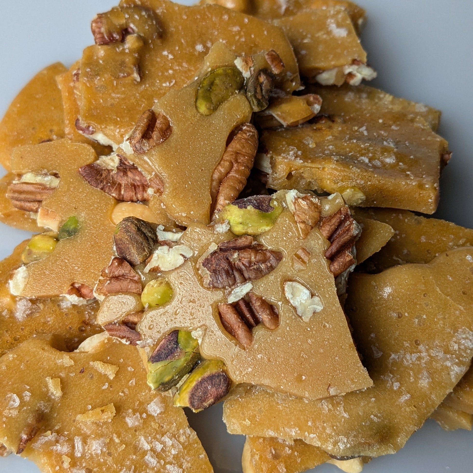 Nut brittle with pistachios and pecans on a gray background