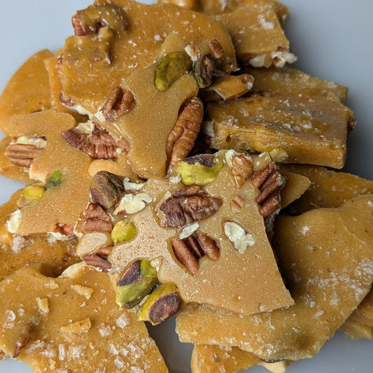 Nut brittle with pistachios and pecans on a gray background